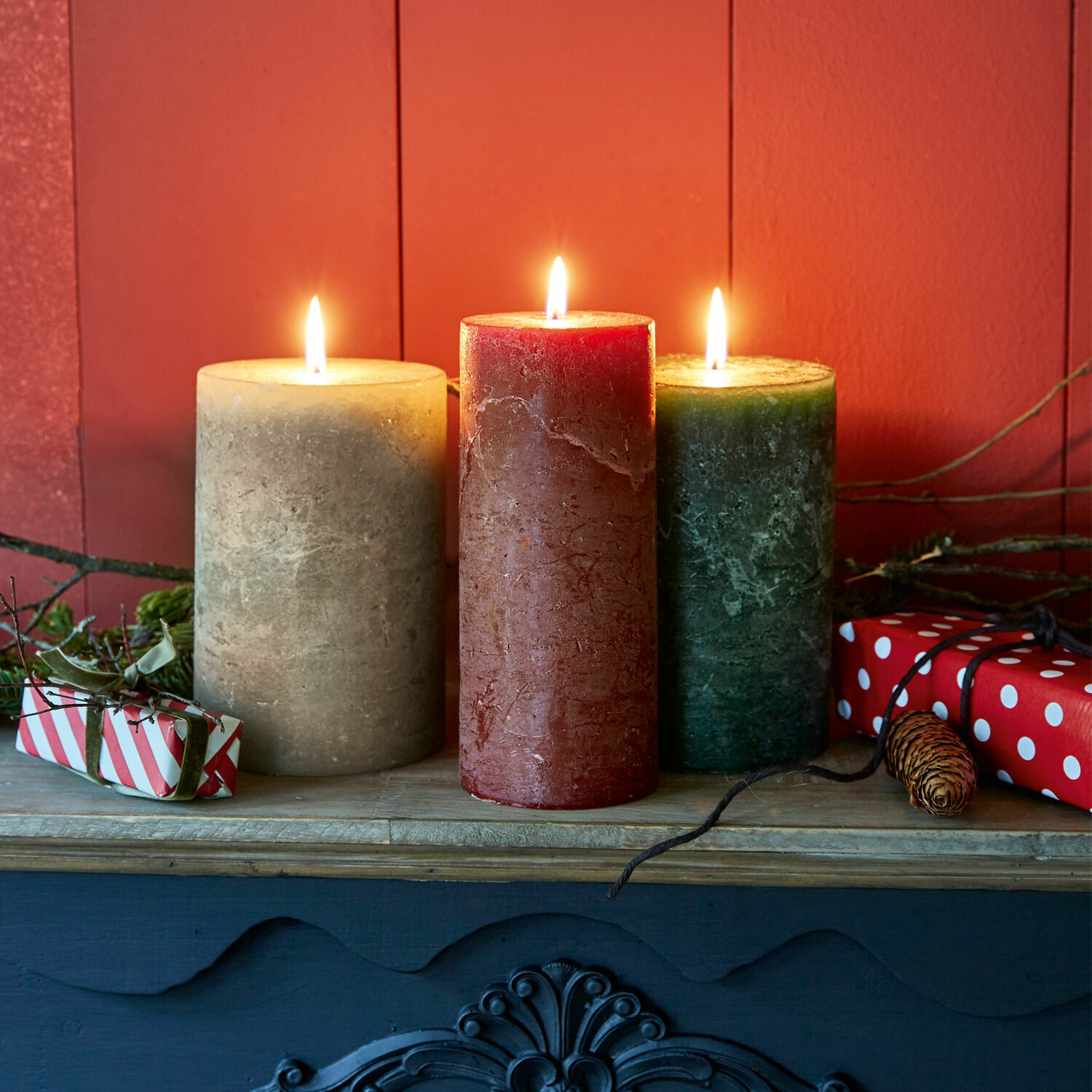 Kerze 3er Set Salis Drei Wachskerzen in Beige, Rot und Grün auf einem Holzregal mit weihnachtlicher Dekoration