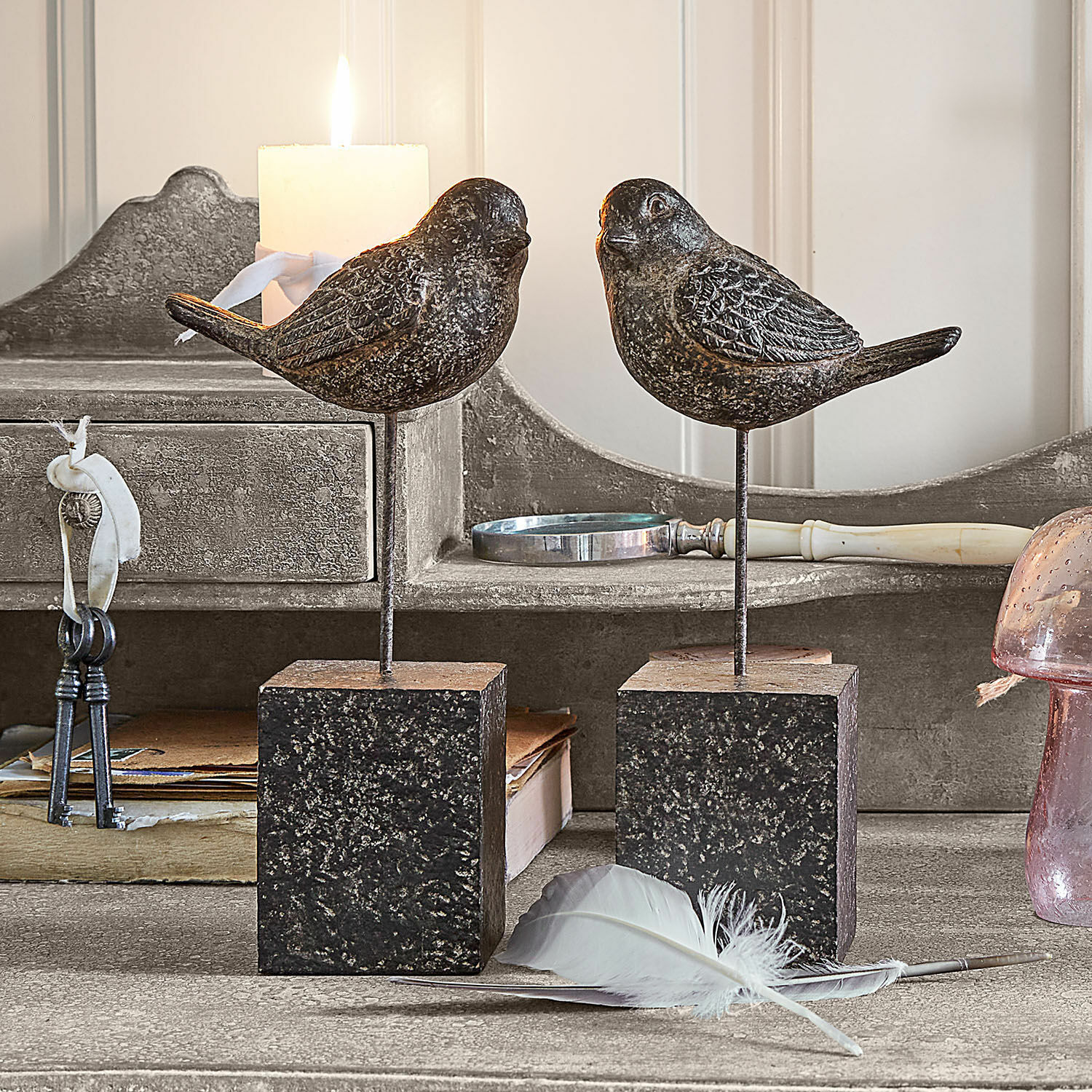 Deko-Vogel 2er Set Juxivel Dekorative Vögel aus dunklem Metall auf quadratischen Ständern auf rustikalem Tisch mit Feder