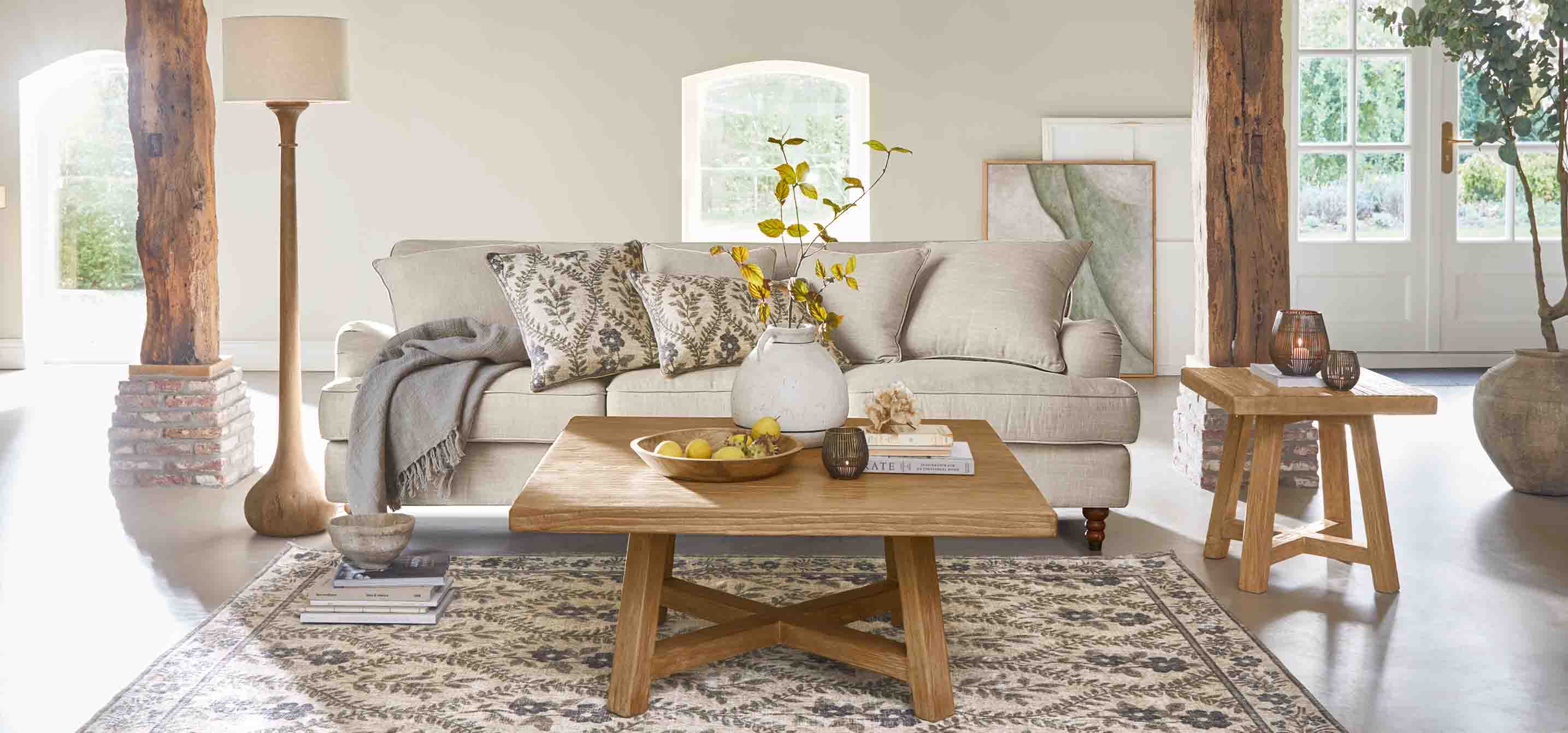 Gemütliches Wohnzimmer mit beigem Sofa, Holztisch und Stehlampe in natürlichen Farbtönen