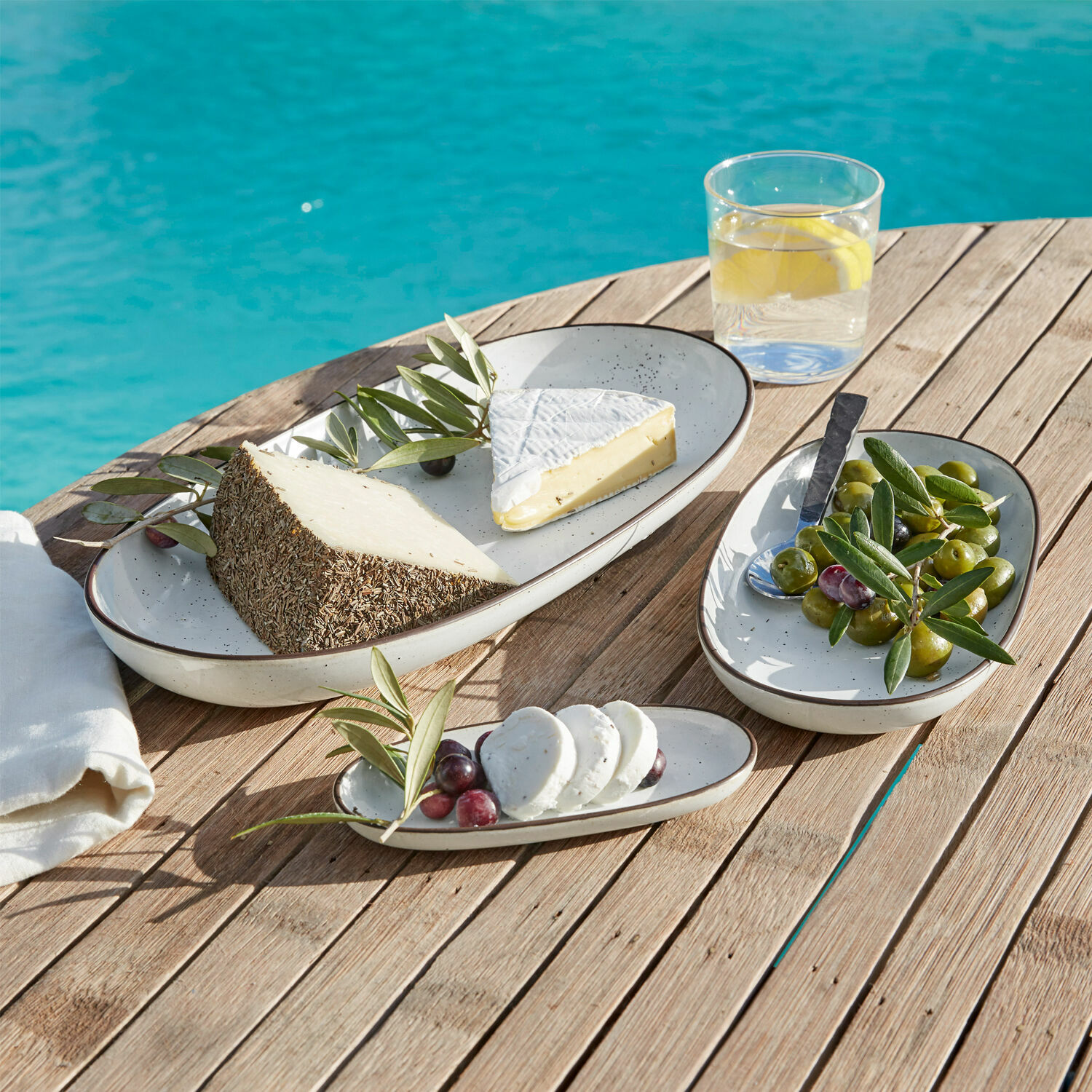 Servierplatte 3er Set Biarré Set aus cremefarbenen ovalen Keramiktellern auf Holztisch mit Käse und Oliven