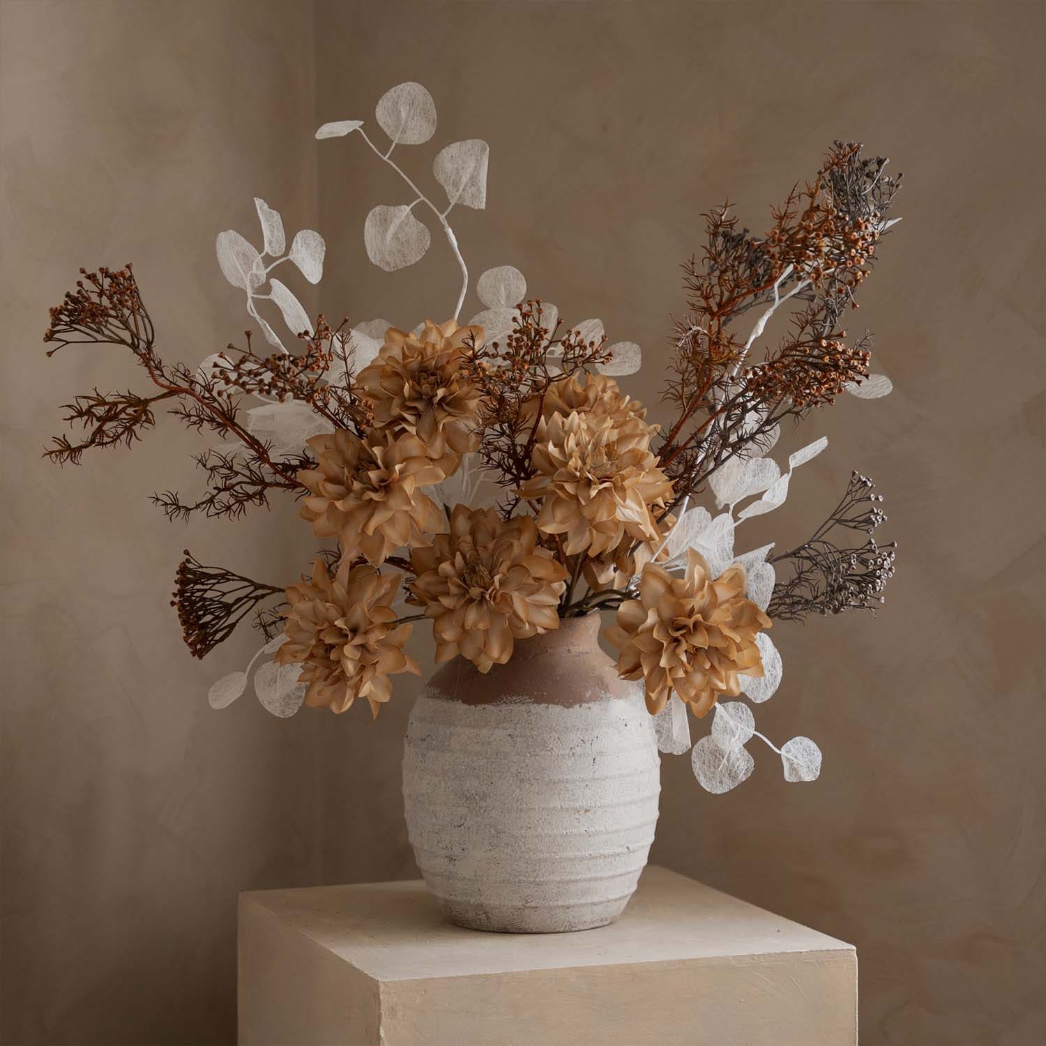 Dekorativer Strauß aus künstlichen Blumen in beige-weißer Vase auf hellem Hintergrund für Wohnraum