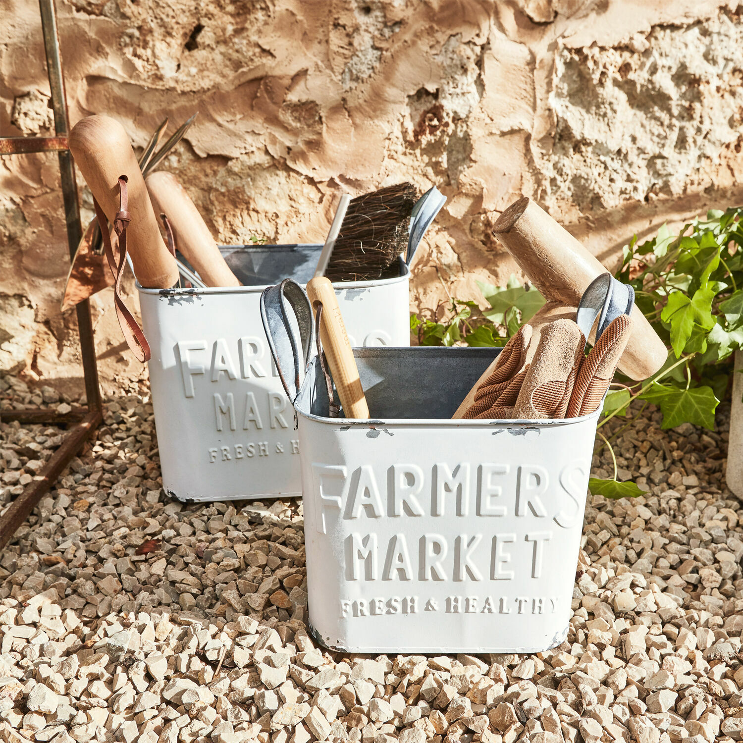 Korb 2er Set Market Weisse Metallbehälter Farmers Market mit Gartengeräten auf kiesigem Boden