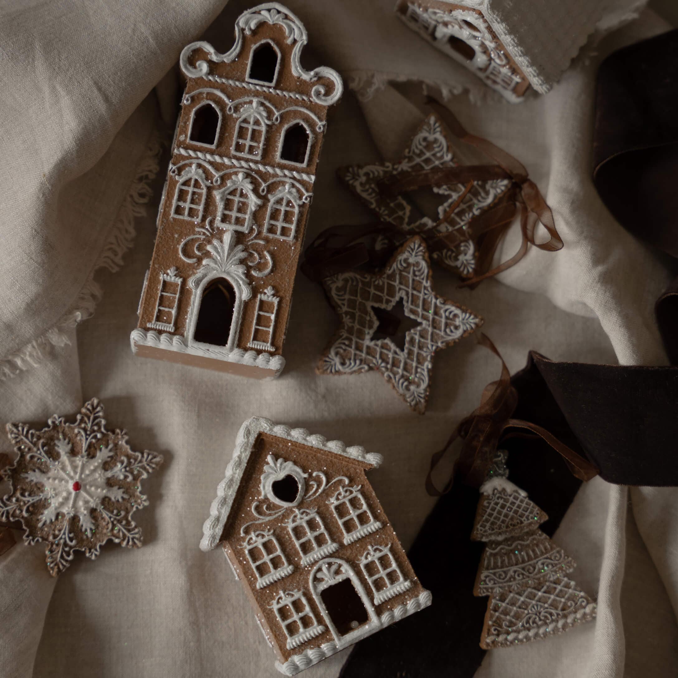 Lebkuchenhäuser und Sterne mit weisser Zuckerglasur auf Leinenstoff, Weihnachtsdekoration