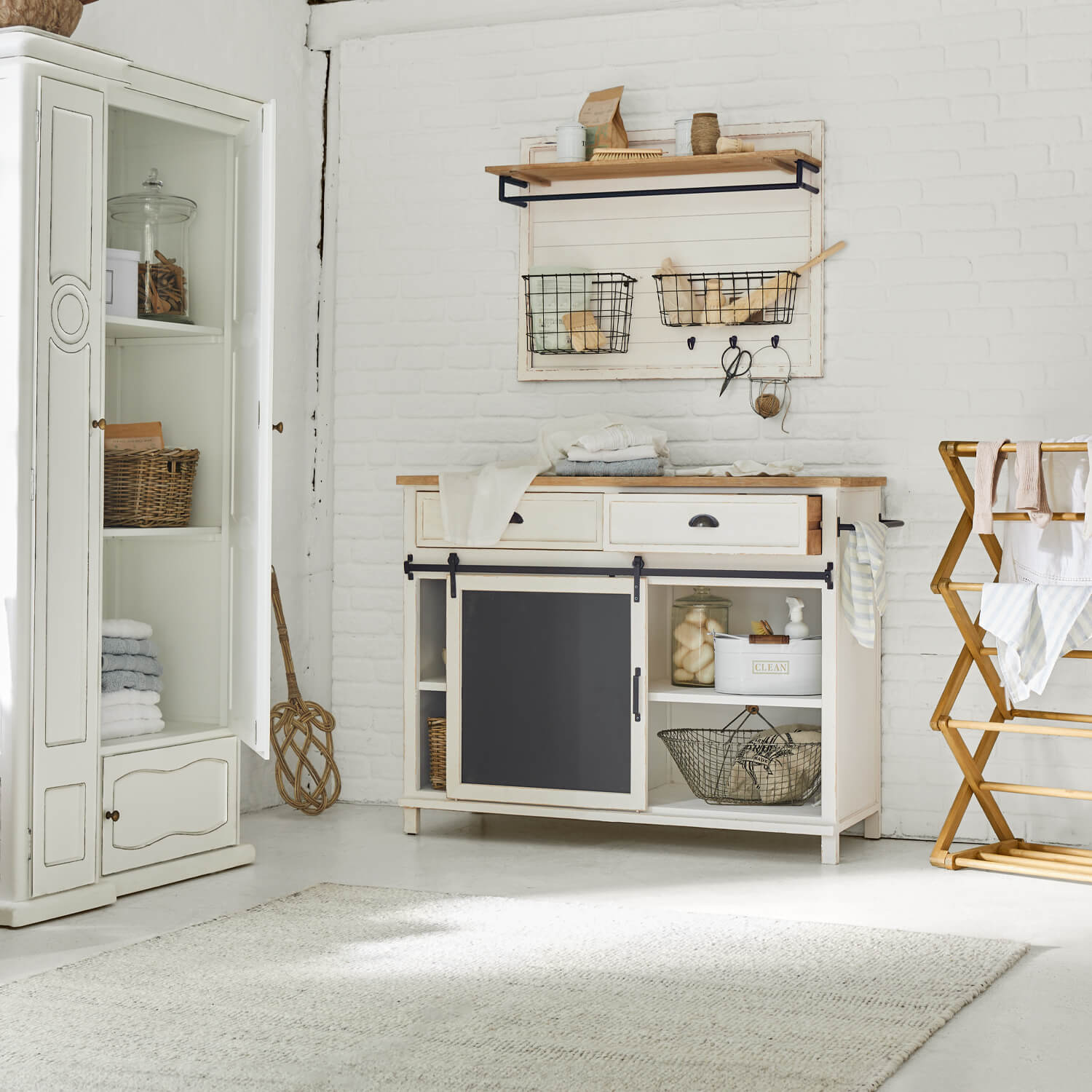 Weisse Holzkommode mit schwarzer Schiefertafel und Wandregal mit Metallkörben im Vintage-Stil