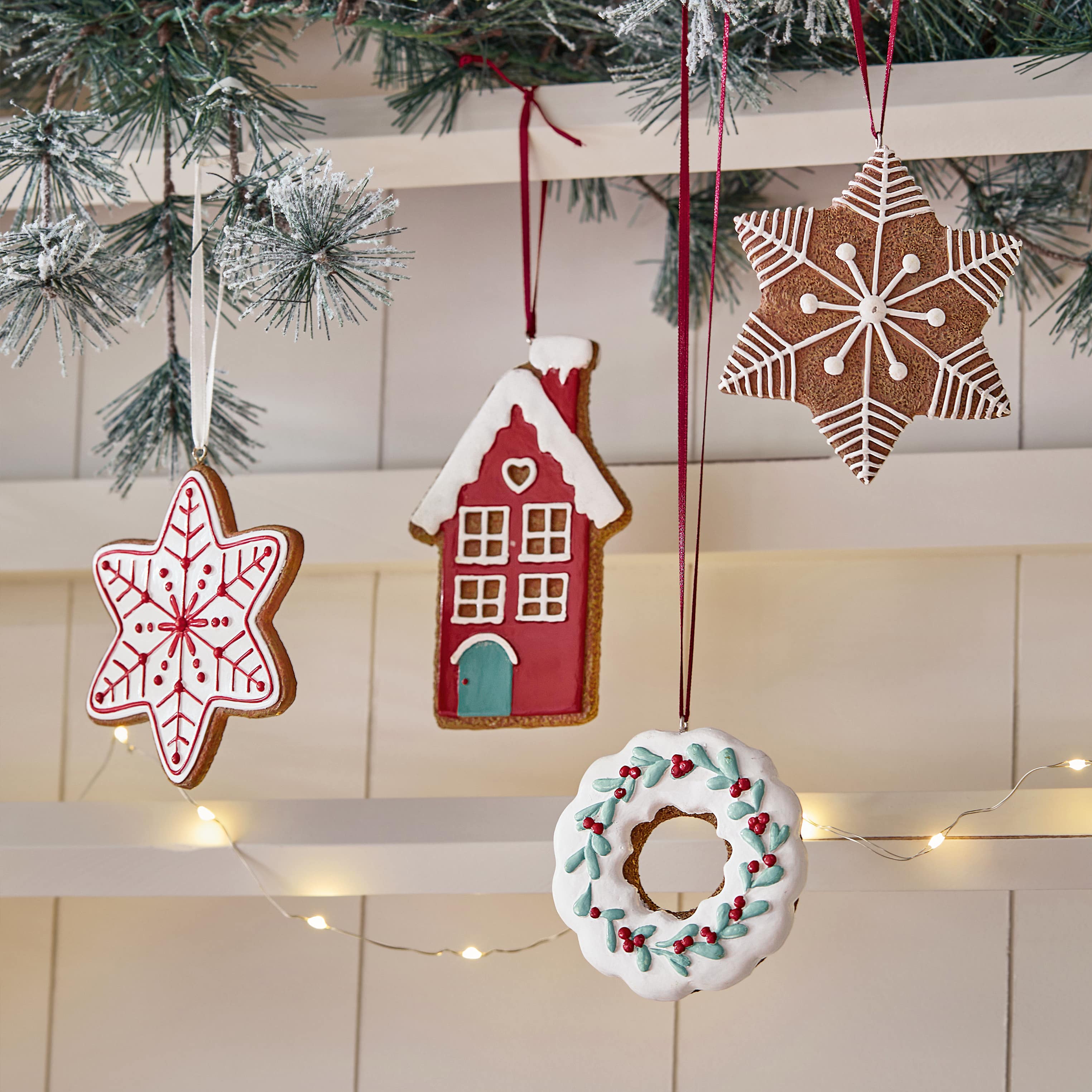 Lebkuchen-Christbaumschmuck in Stern-, Haus- und Kranzform mit buntem Zuckerguss an Tannenzweig