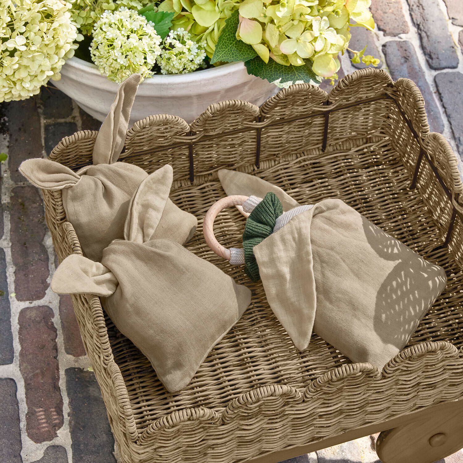 Säckchen 3er Set Snugglewood Beige Leinenbeutel mit Ohren in einem Weidenkorb vor Blumen und Ziegelboden