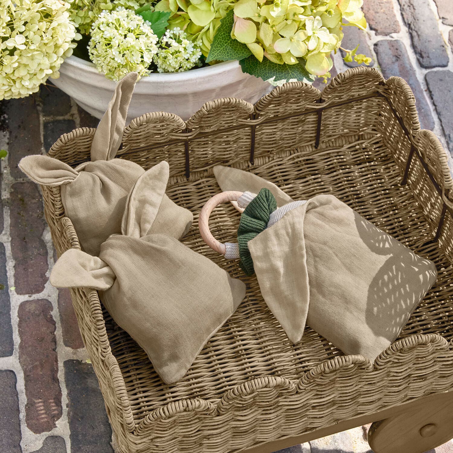 Säckchen 3er Set Snugglewood Beige Leinenbeutel mit Ohren in einem Weidenkorb vor Blumen und Ziegelboden
