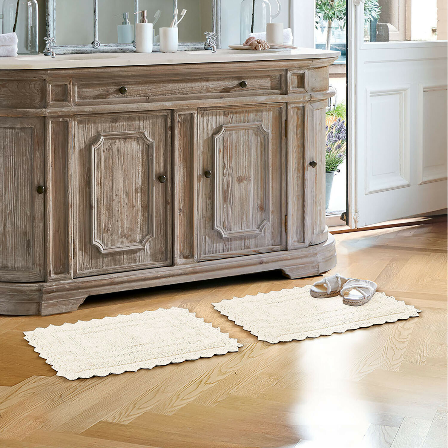 Badematte Yalexir Vintage-Holzkommode mit zwei cremefarbenen Teppichen auf hellem Boden in einem hellen Badezimmer