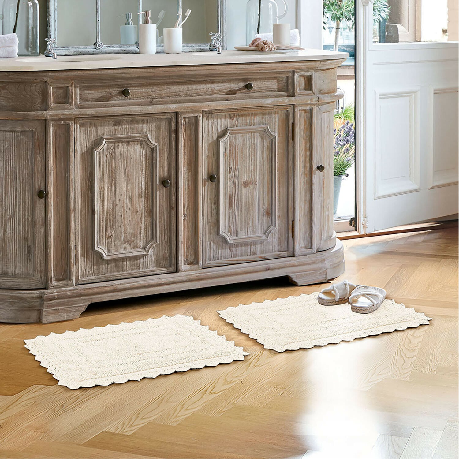 Badematte Yalexir Vintage-Holzkommode mit zwei cremefarbenen Teppichen auf hellem Boden in einem hellen Badezimmer