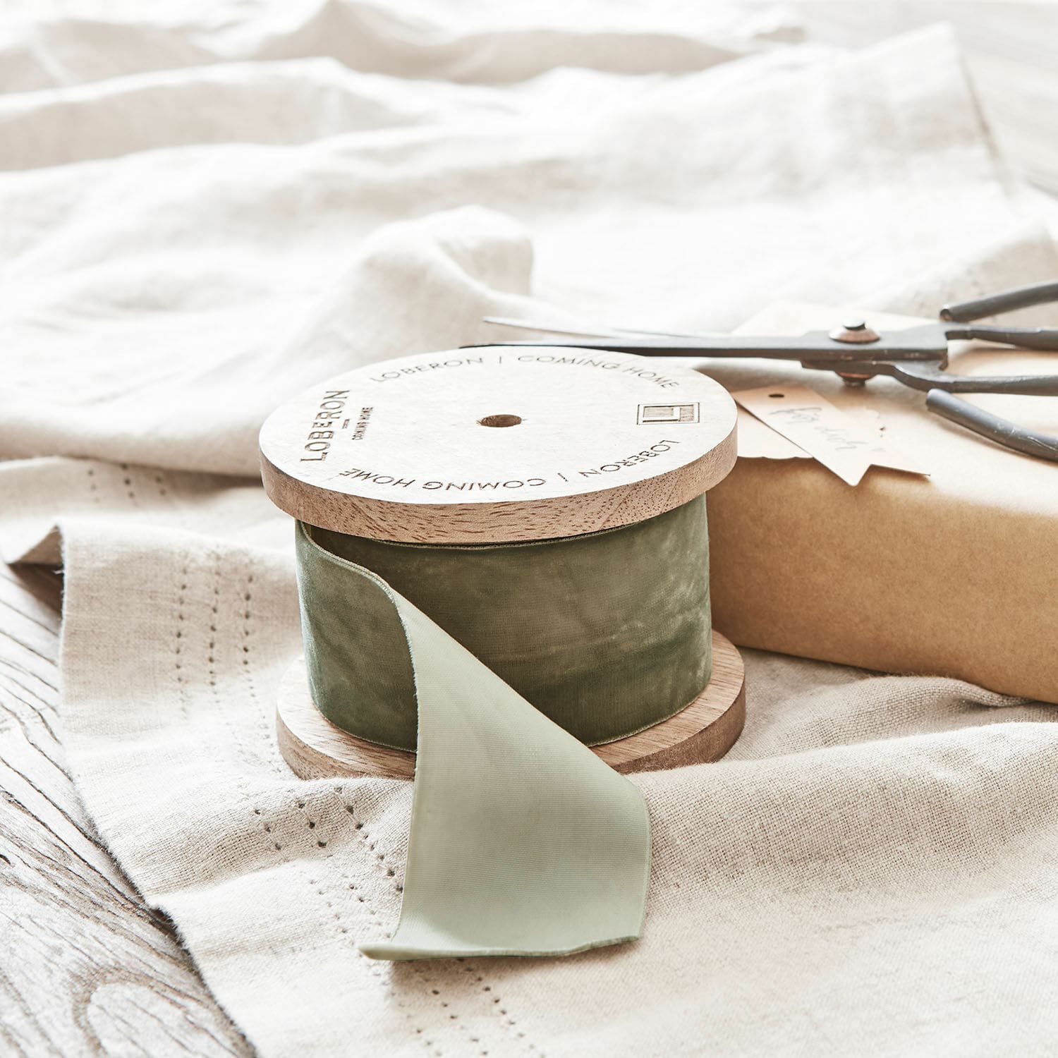 Samtband Phaedra Grünes Samtband auf Holzspule auf Leinenstoff mit Schere und Geschenkverpackung