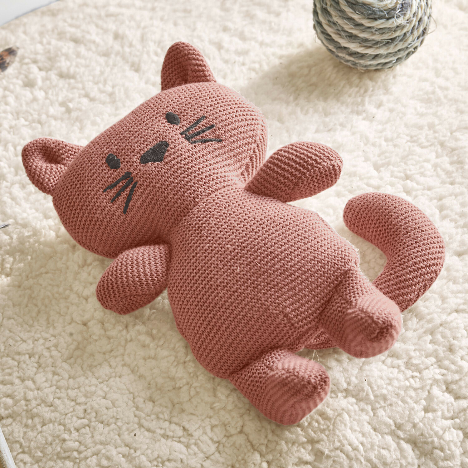 Katzenspielzeug Mewlie Rosa gestrickte Baumwoll-Katzenpuppe auf weißem weichem Teppich, Kinderstofftier