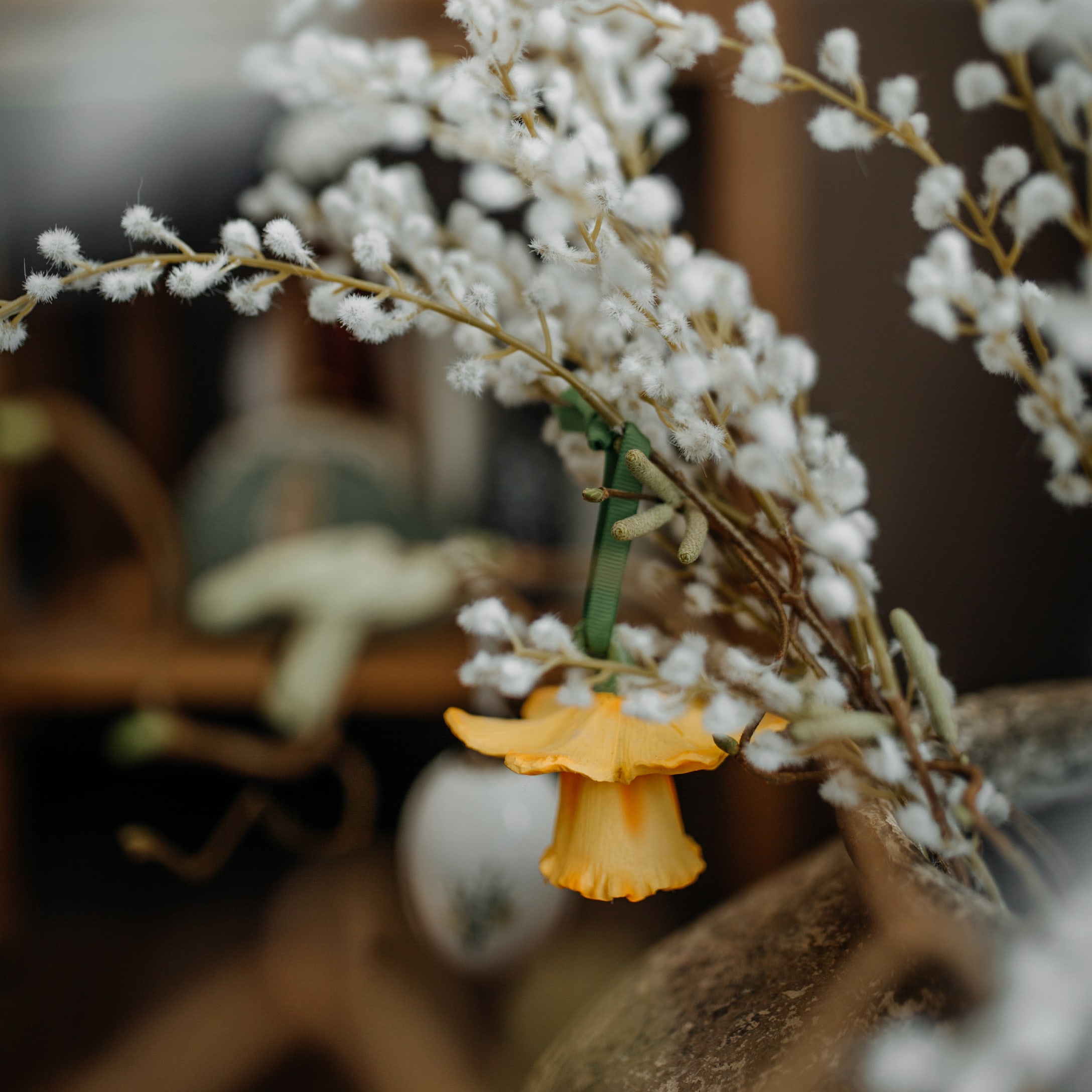 Osterdekoration mit weissen flauschigen Zweigen und gelber Blüte für Wohnräume