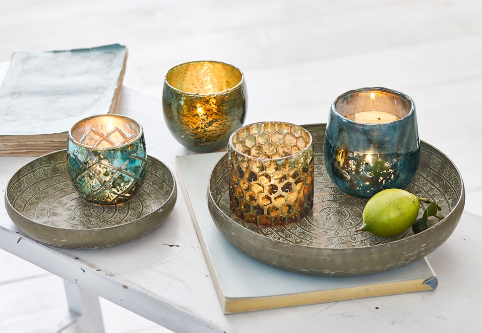 Orientalische Metalltabletts mit gold-blauen dekorativen Kerzenhaltern auf weissem Tisch