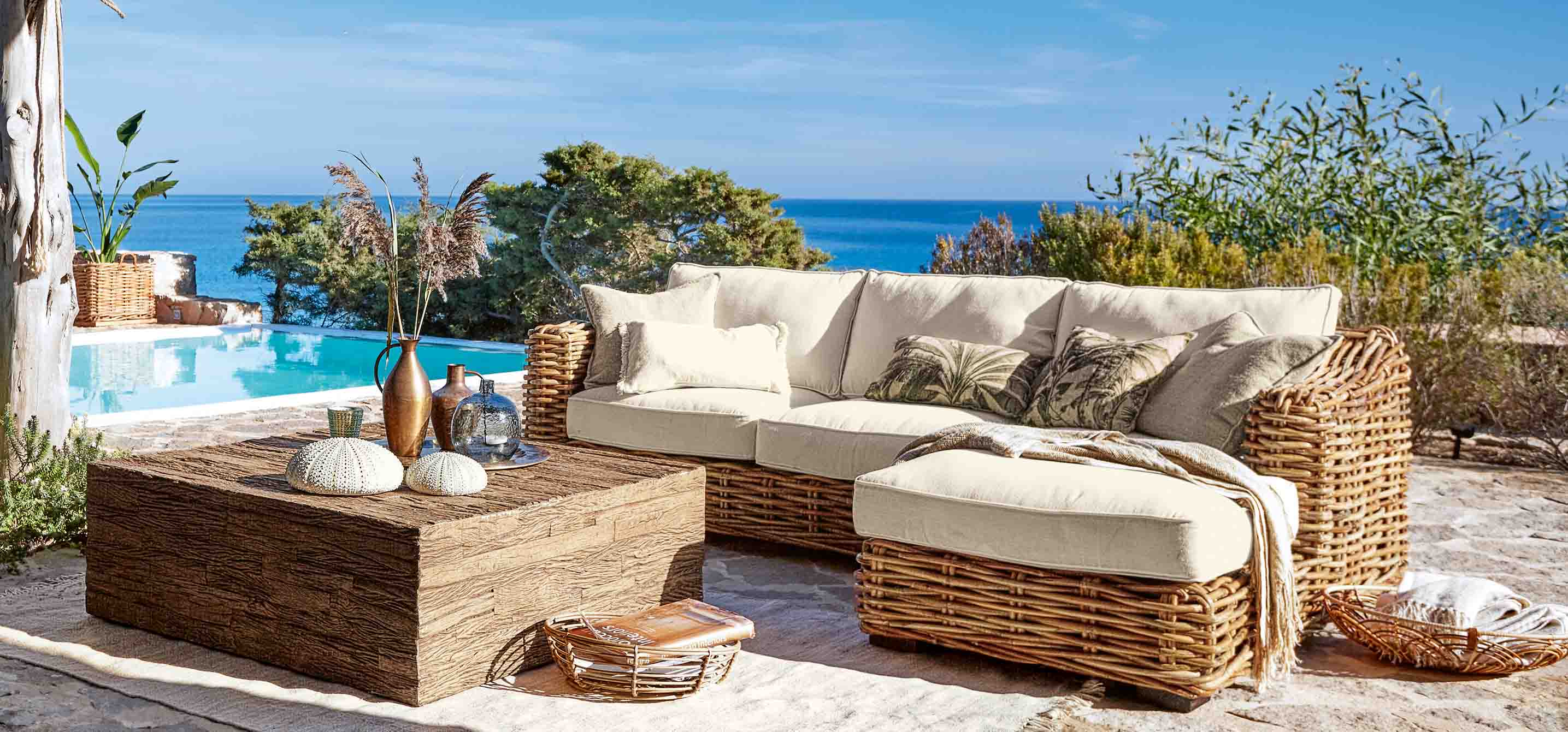 Rattan-Gartenmöbel mit cremefarbenen Polstern am Pool mit Meerblick
