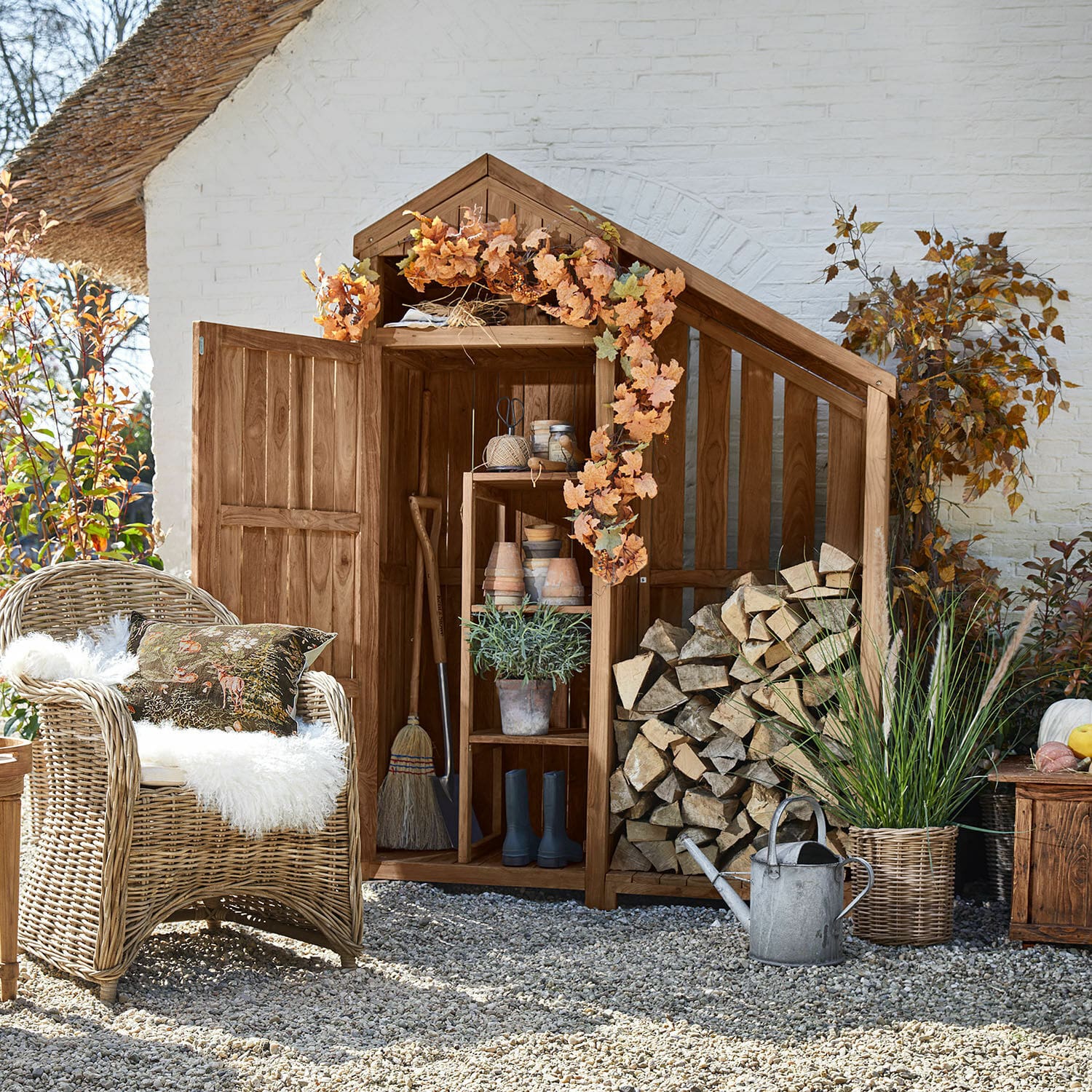 Gartenschrank Briancourt Gartenschrank aus Holz mit offener Tür, herbstlicher Dekoration und gestapeltem Brennholz draussen