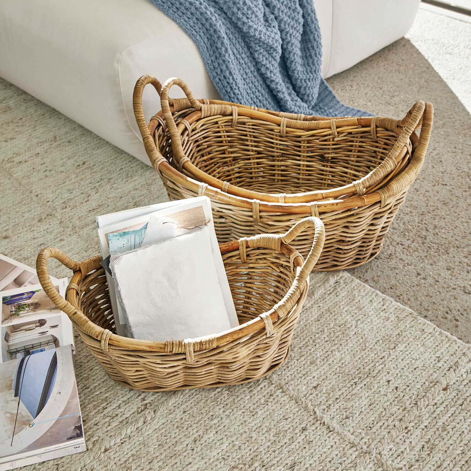 Zwei natürliche Rattankörbe auf Teppich, einer mit Zeitschriften gefüllt, praktischer Aufbewahrungskorb
