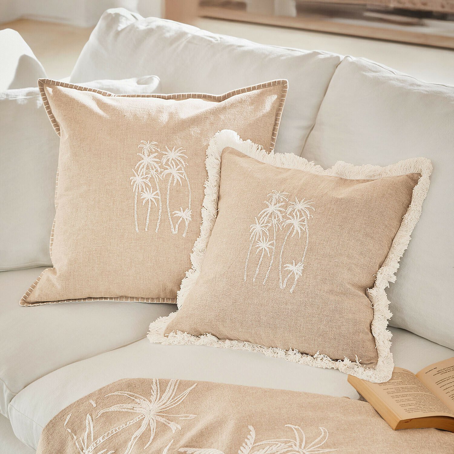Beige Leinenkissen mit weisser Palmenstickerei auf hellem Sofa, dekorative Wohntextilien
