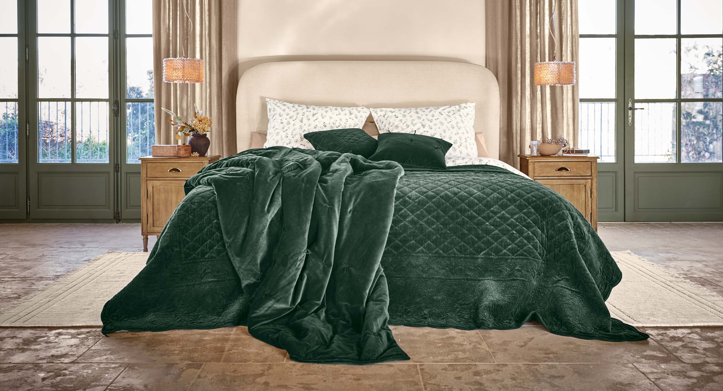 Gemütliches Schlafzimmer mit Bett und dunkelgrünem Samtüberwurf sowie passenden Kissen