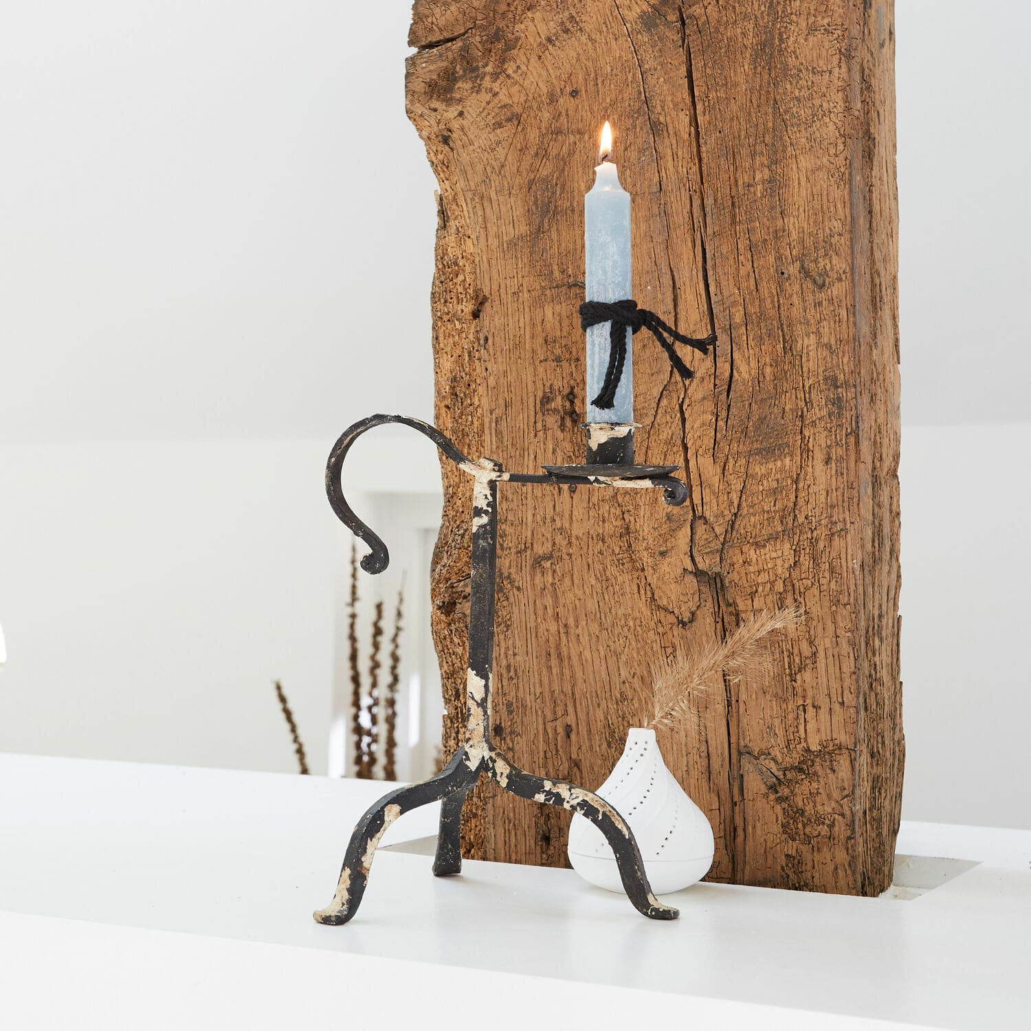 Kerzenhalter Minorville Metall-Kerzenhalter mit abgenutztem schwarzem Lack und blauer Kerze vor weissem und Holz-Hintergrund