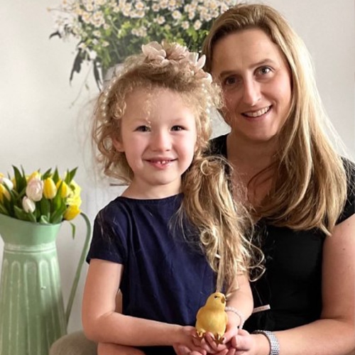 Lächelnde Frau und Mädchen mit Vogeldekoration in hellem Raum mit Blumen
