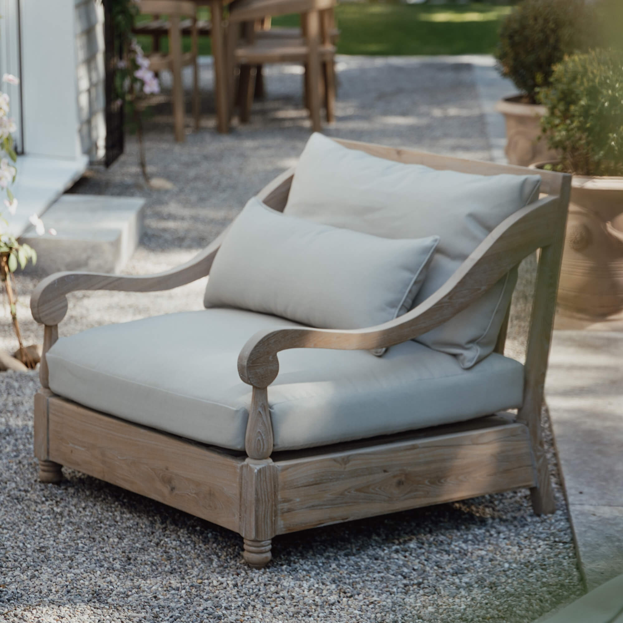 Gartensofa aus hellem Holz mit cremefarbenen Kissen, bequeme Terrassenmöbel