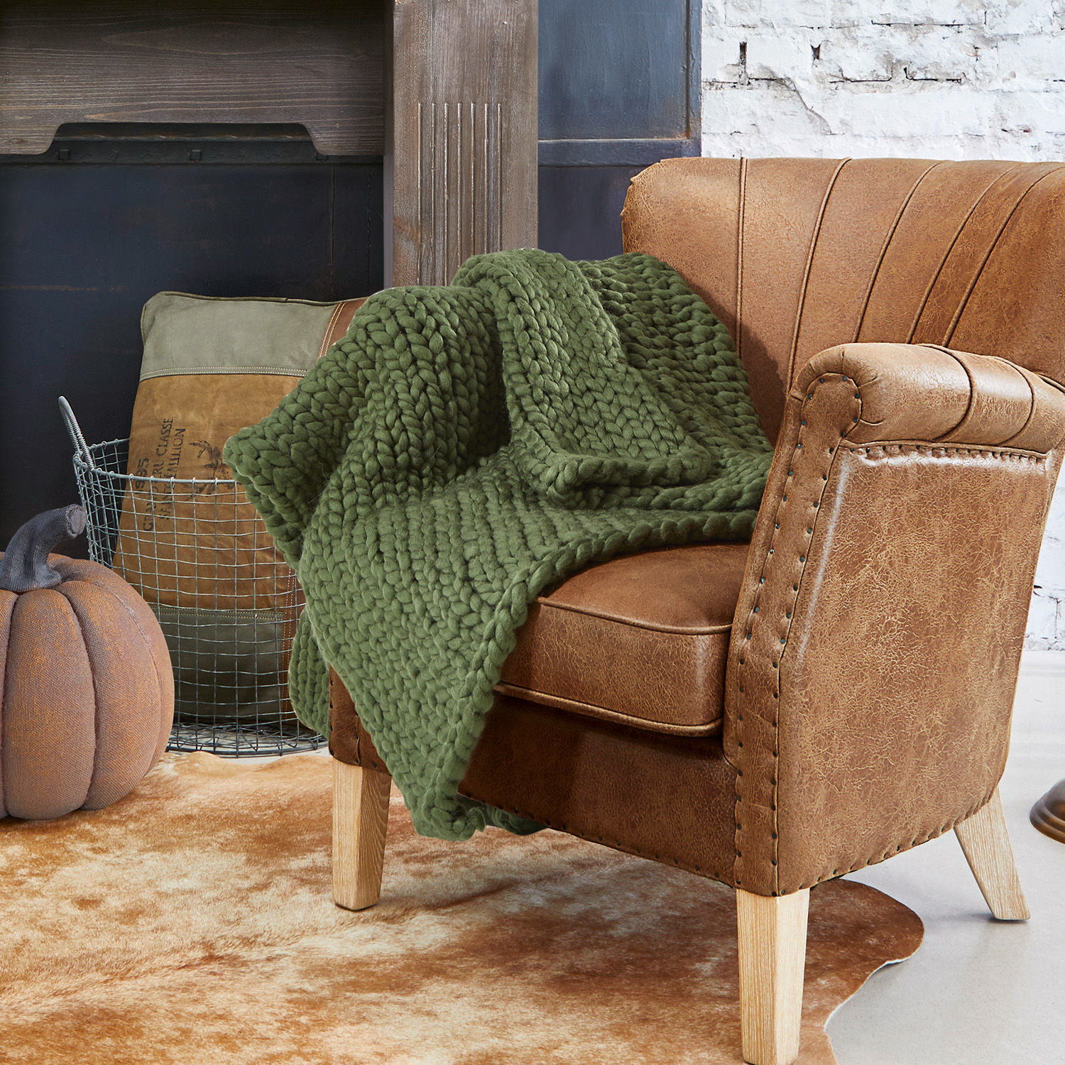 Plaid Reidous Brauner Kunstledersessel mit grünem, grob gestricktem Plaid auf hellem Vintage-Teppich