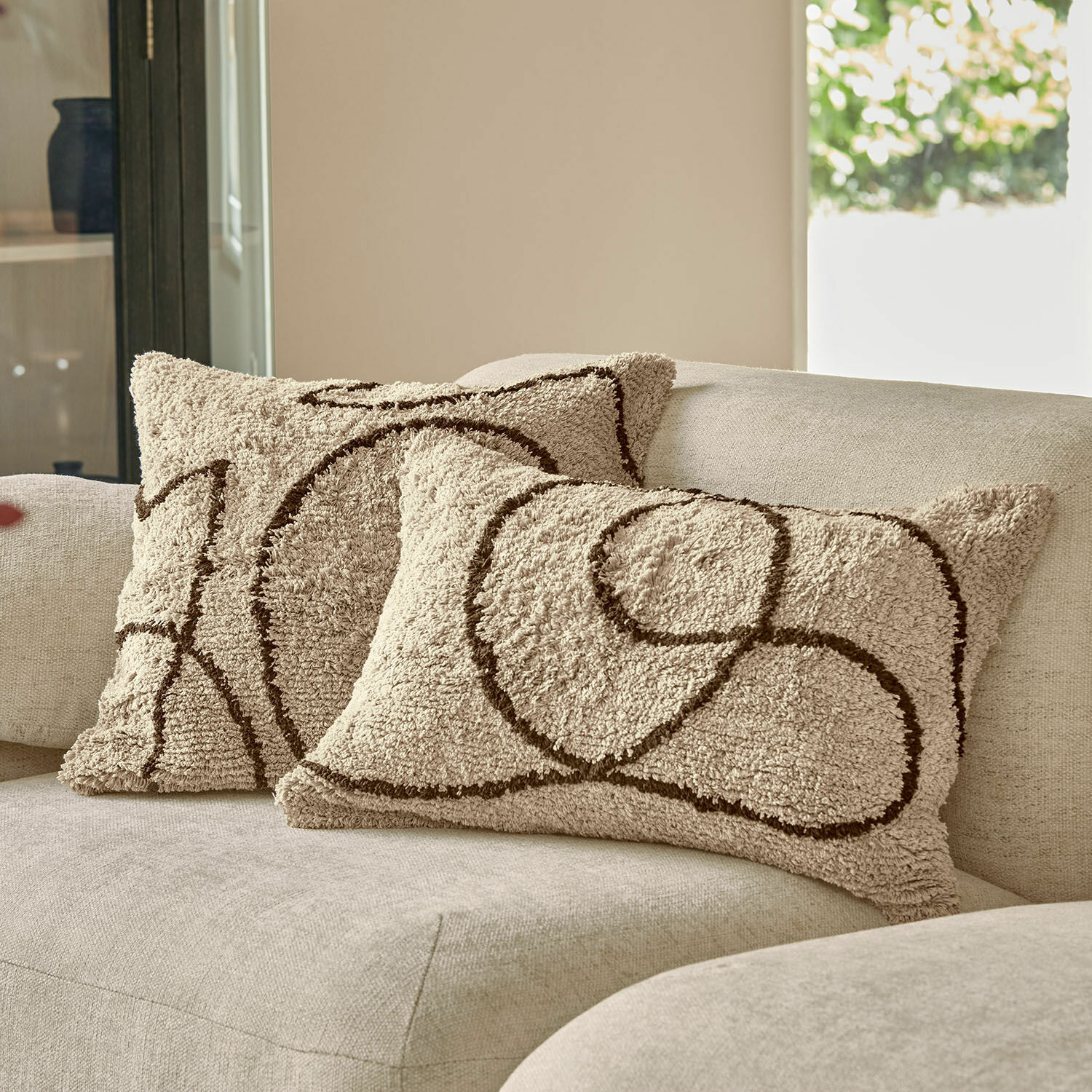 Kissenhülle 2er Set Lavinois Beige dekorative Kissen aus weichem Material mit braunem geometrischem Muster auf hellem Sofa.