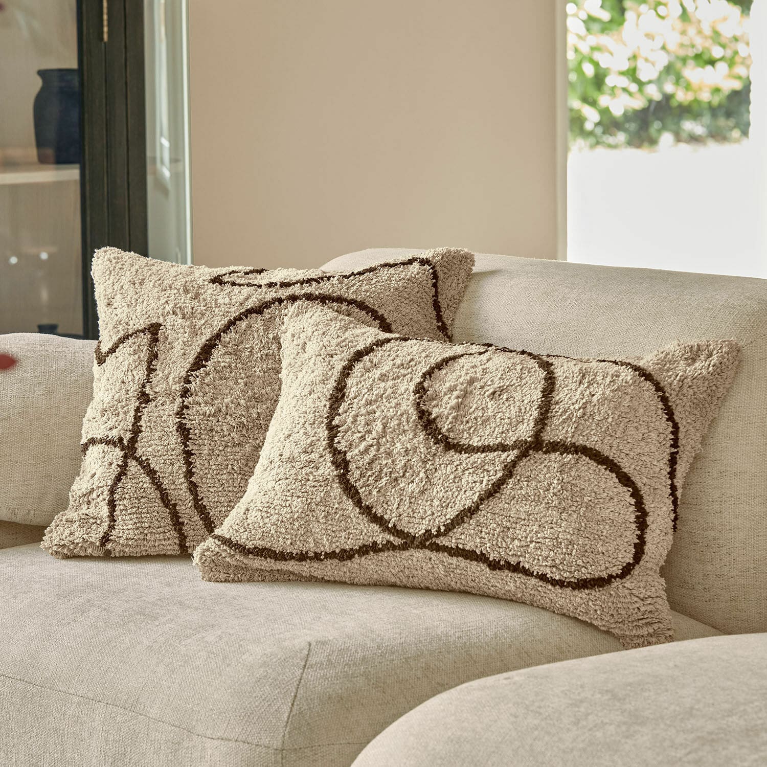 Kissenhülle 2er Set Lavinois Beige dekorative Kissen aus weichem Material mit braunem geometrischem Muster auf hellem Sofa.