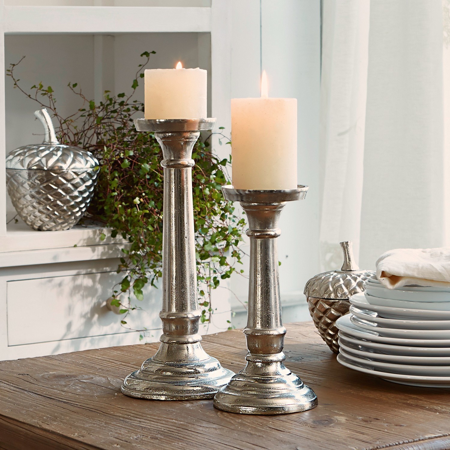 Kerzenständer 2er Set Symone Zwei silberne Metallkerzenhalter mit weissen Kerzen auf Holztisch als Wohnaccessoire