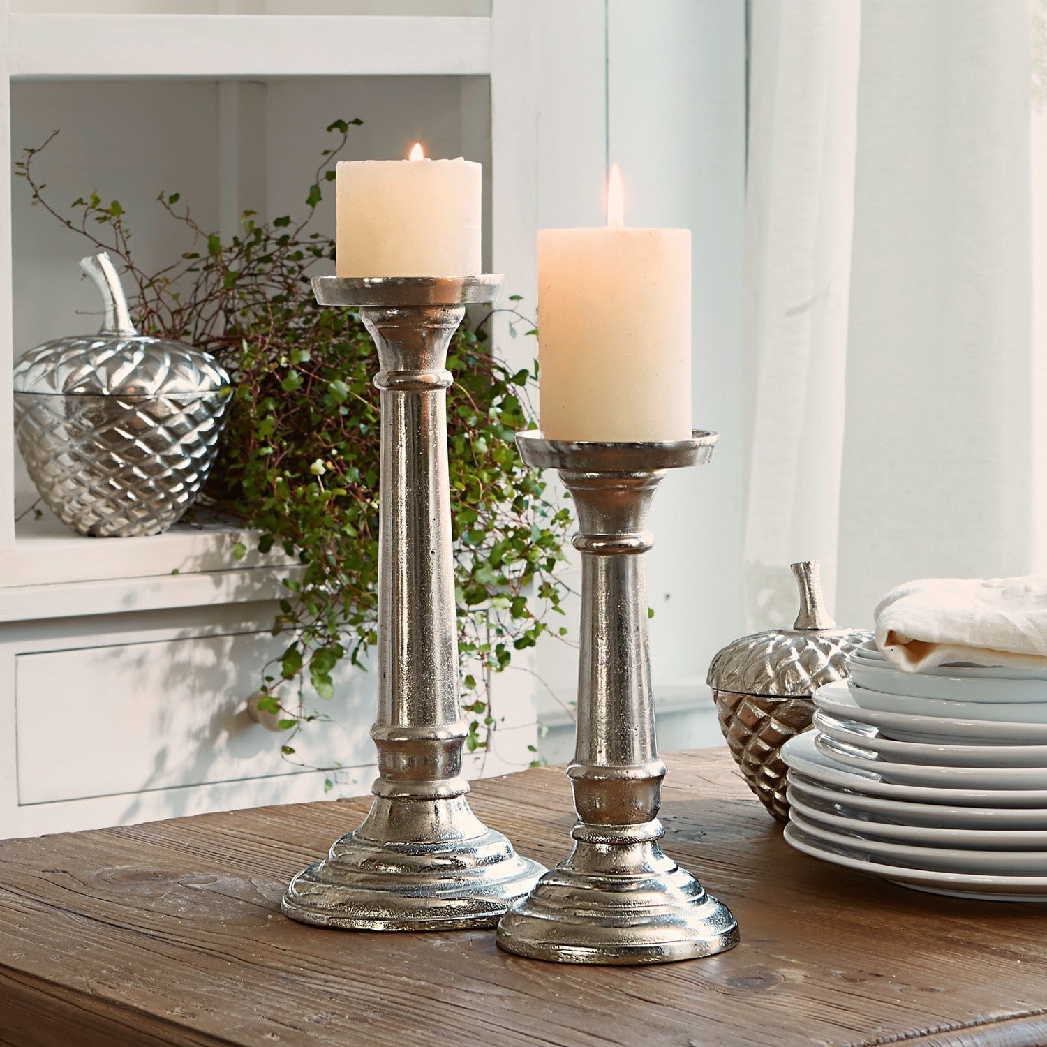 Kerzenständer 2er Set Symone Zwei silberne Metallkerzenhalter mit weissen Kerzen auf Holztisch als Wohnaccessoire