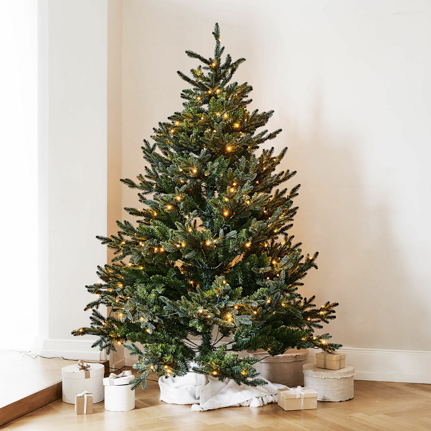 Weihnachtsbaum Franck Künstlicher grüner Weihnachtsbaum mit warmweissen LED-Lichtern auf Holzboden mit Geschenken