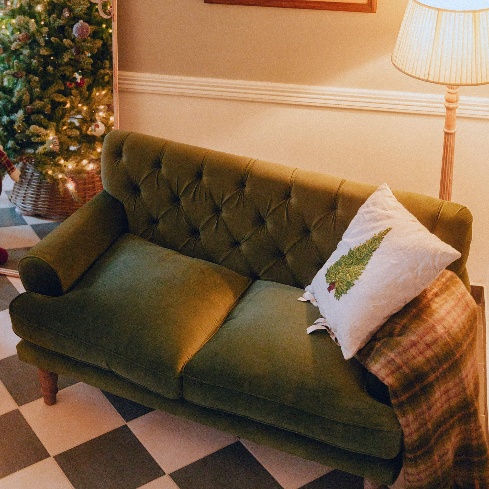 Grünes Samtsofa mit gesteppter Rückenlehne und Weihnachtskissen in gemütlichem Zimmer