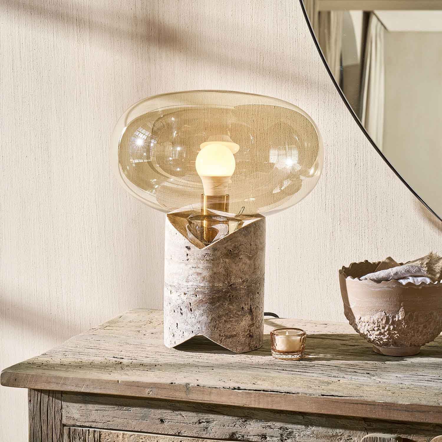 Tischlampe mit Marmorfuß und transparentem beigem Glasschirm auf rustikalem Holztisch