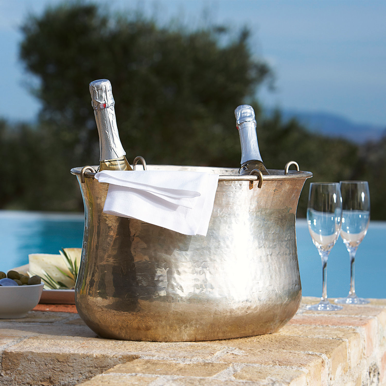 Sektkühler Montgomery Messer gehämmerter Kupfereiseimer mit zwei Champagnerflaschen und weisser Serviette auf der Terrasse
