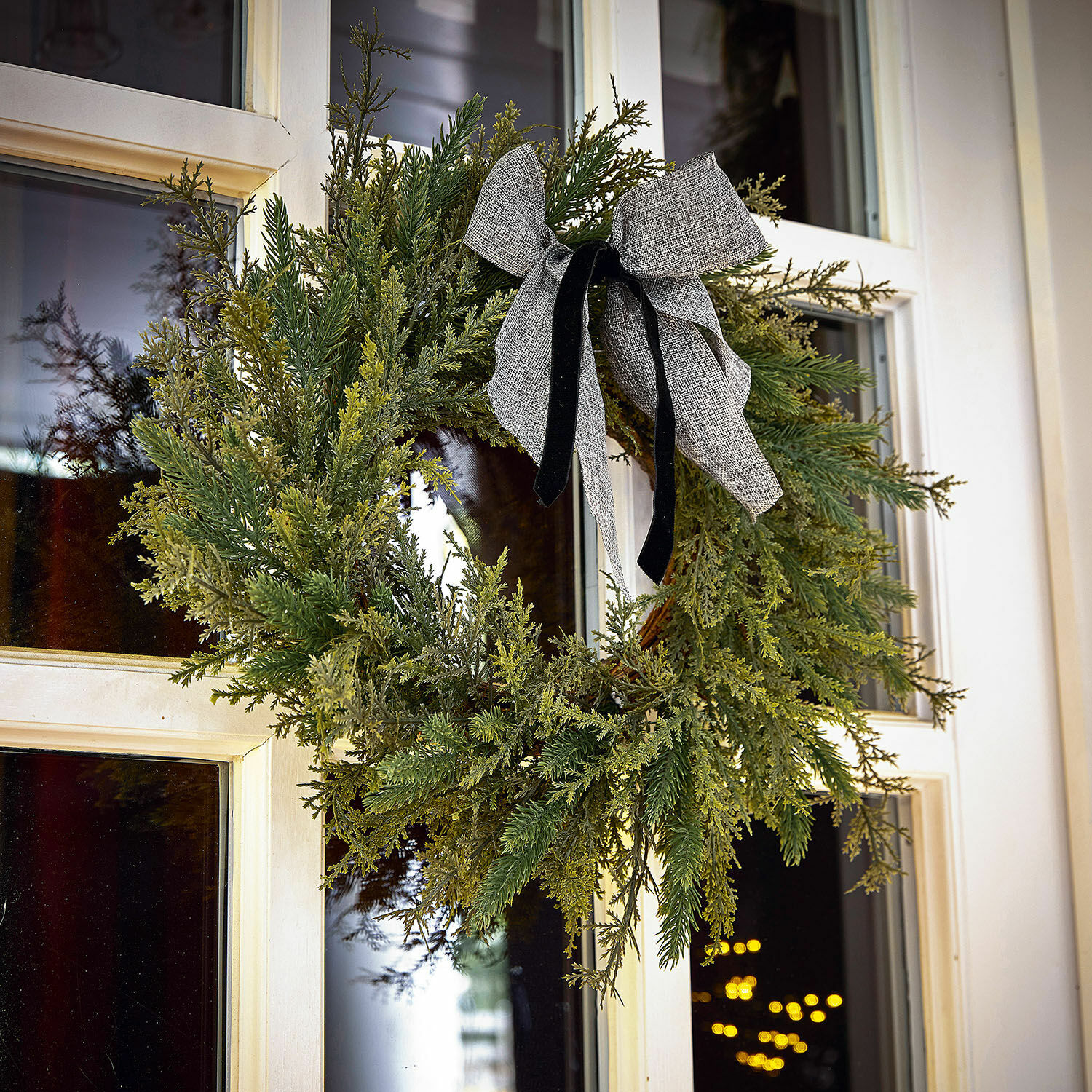 Kranz Julien Weihnachtskranz aus grünen Zweigen mit grauer Schleife an weisser Haustür