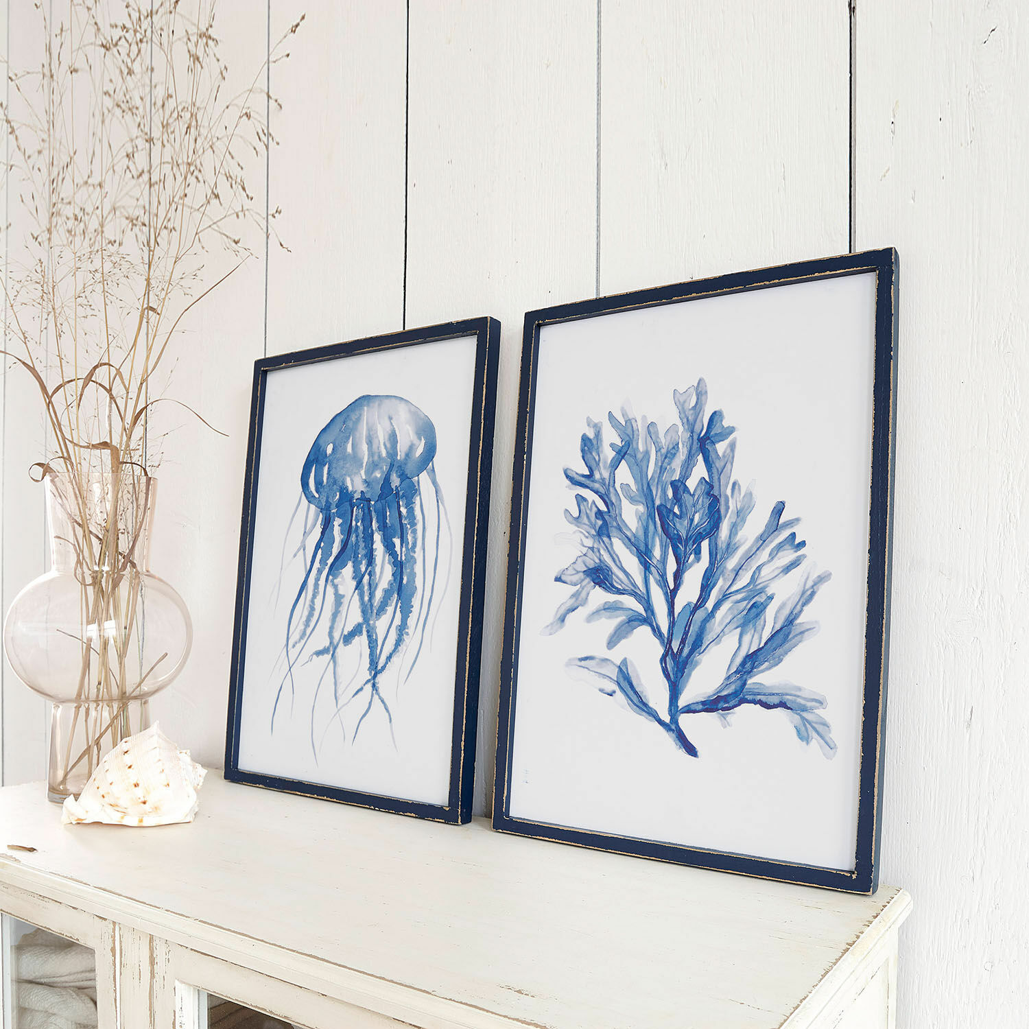 Wandbild 2er Set Dewey Zwei maritime Bilder in blauen Rahmen auf weissem Sideboard, stilvolle Wohnraumdekoration.