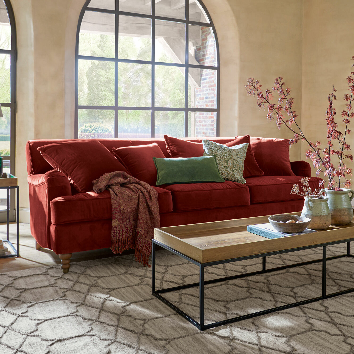 Sofa Isa Rotes Samtsofa mit Kissen und Holzcouchtisch im hellen Wohnzimmer