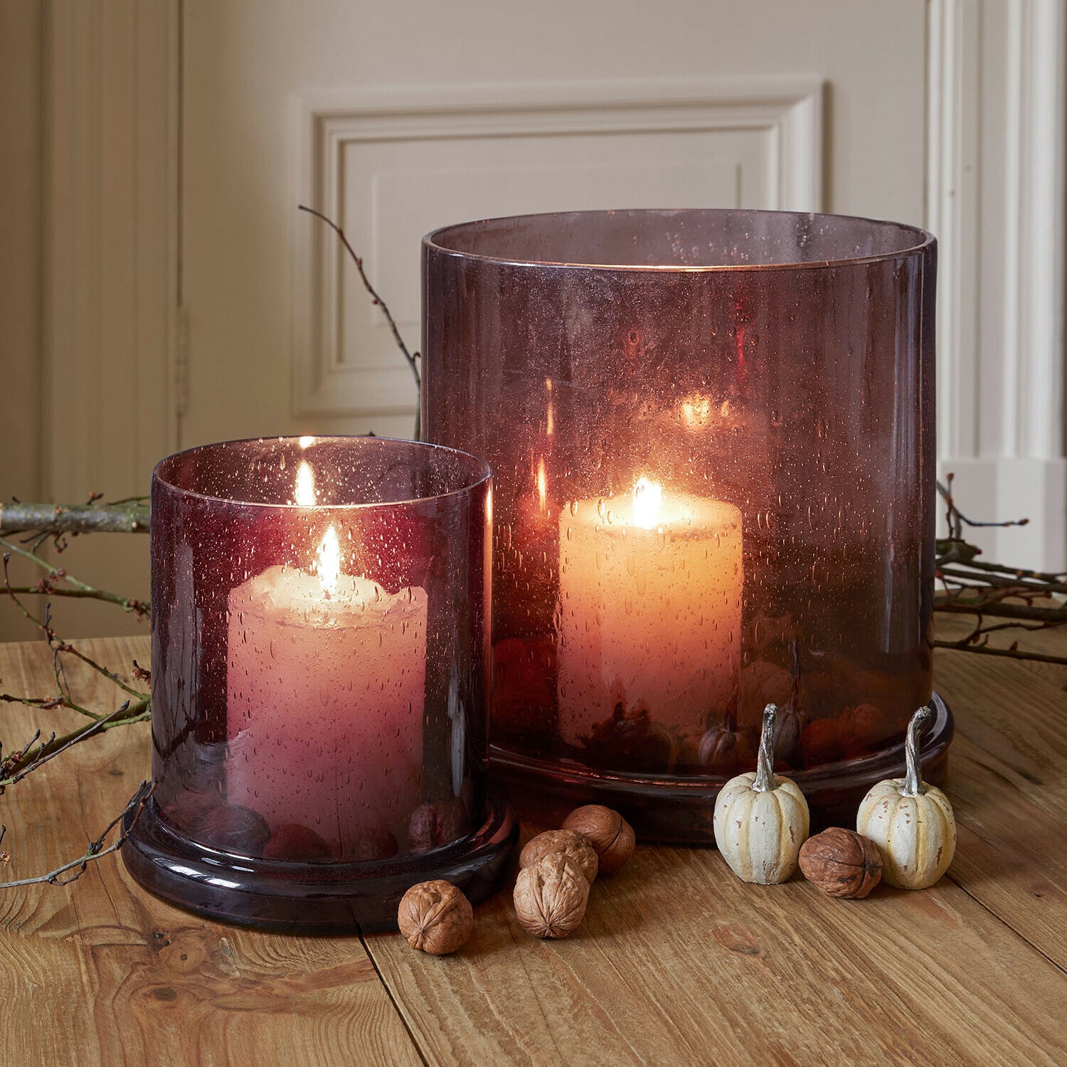 Windlicht 2er Set Saffrone Zwei brennende Kerzen in violetten Glaswindlichtern auf Holztisch mit herbstlicher Dekoration