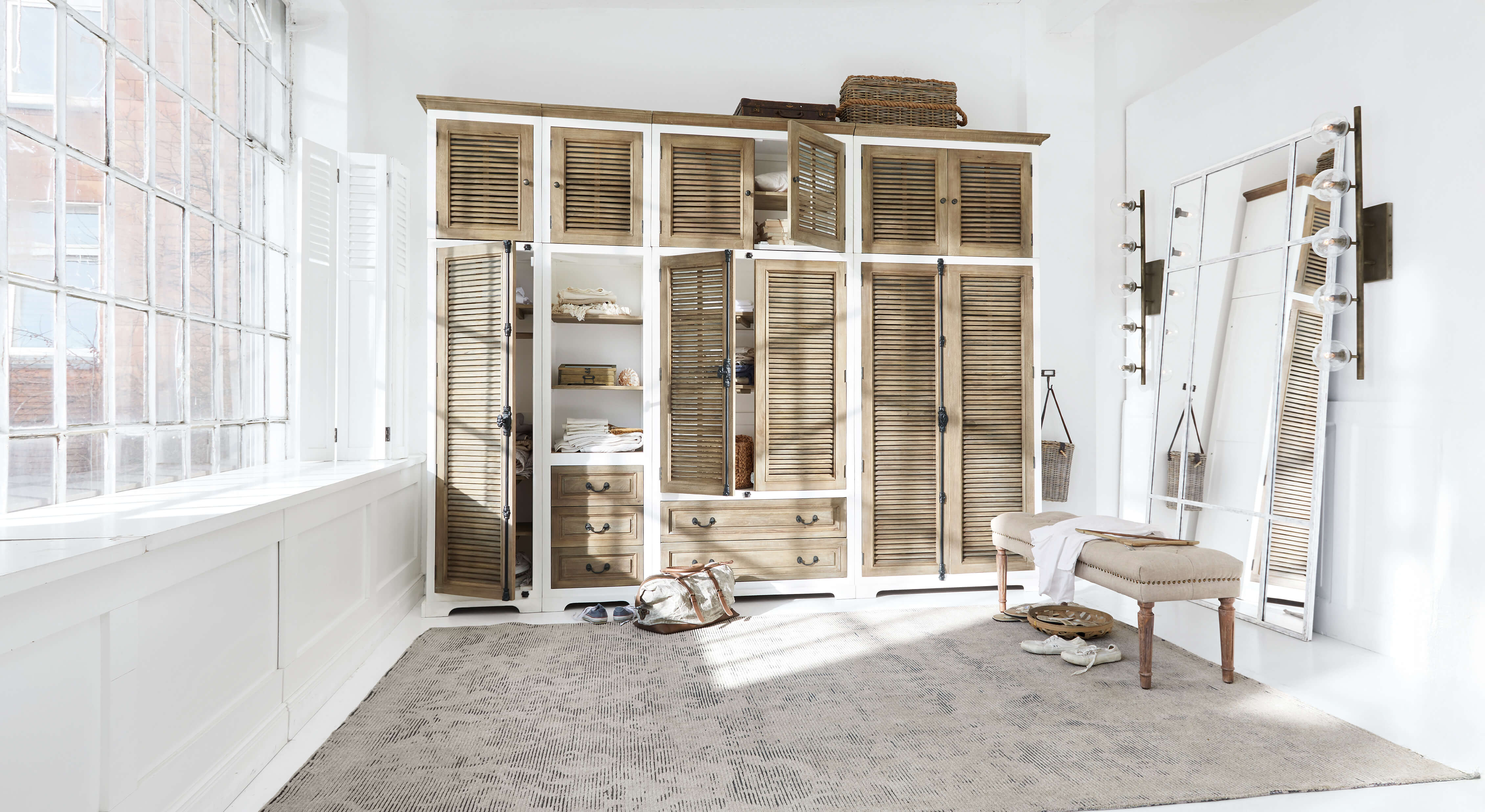 Großer Kleiderschrank aus weißem und naturfarbenem Holz mit Lamellentüren und großem Spiegel in hellem Raum