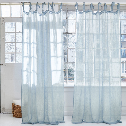 Leichte, hellblaue transparente Vorhänge aus feinem Stoff vor grossem Fenster in modernem Raum.