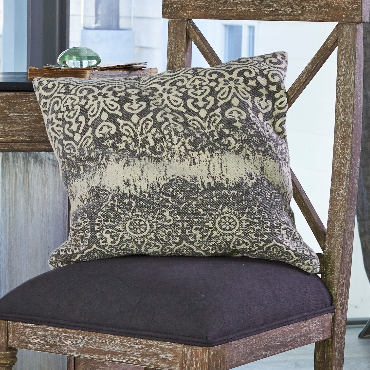 Dekoratives Baumwollkissen in Grau-Beige mit Muster auf Holzstuhl im Wohnzimmer
