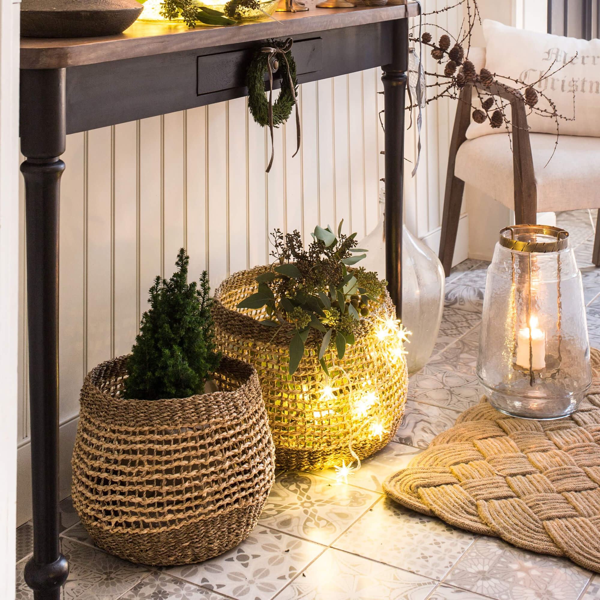 Dekorative Körbe aus Naturmaterial mit grünen Pflanzen und LED-Lichterkette auf dem Boden.