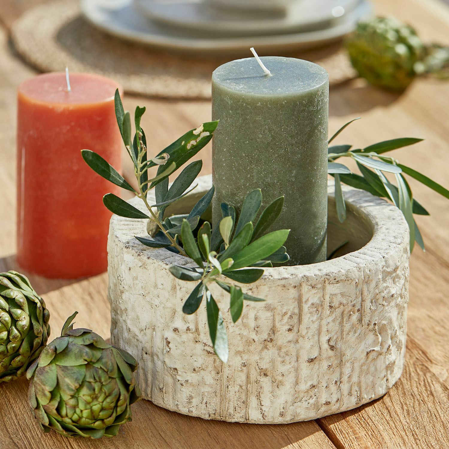 Schale Continas Runder Kerzenhalter aus beigem Stein mit grüner Kerze und Blattdekoration auf Holztisch