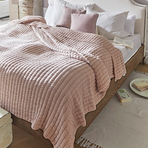 Rosa gesteppte Decke auf Holzbett mit weissen Kissen in gemütlichem Schlafzimmer