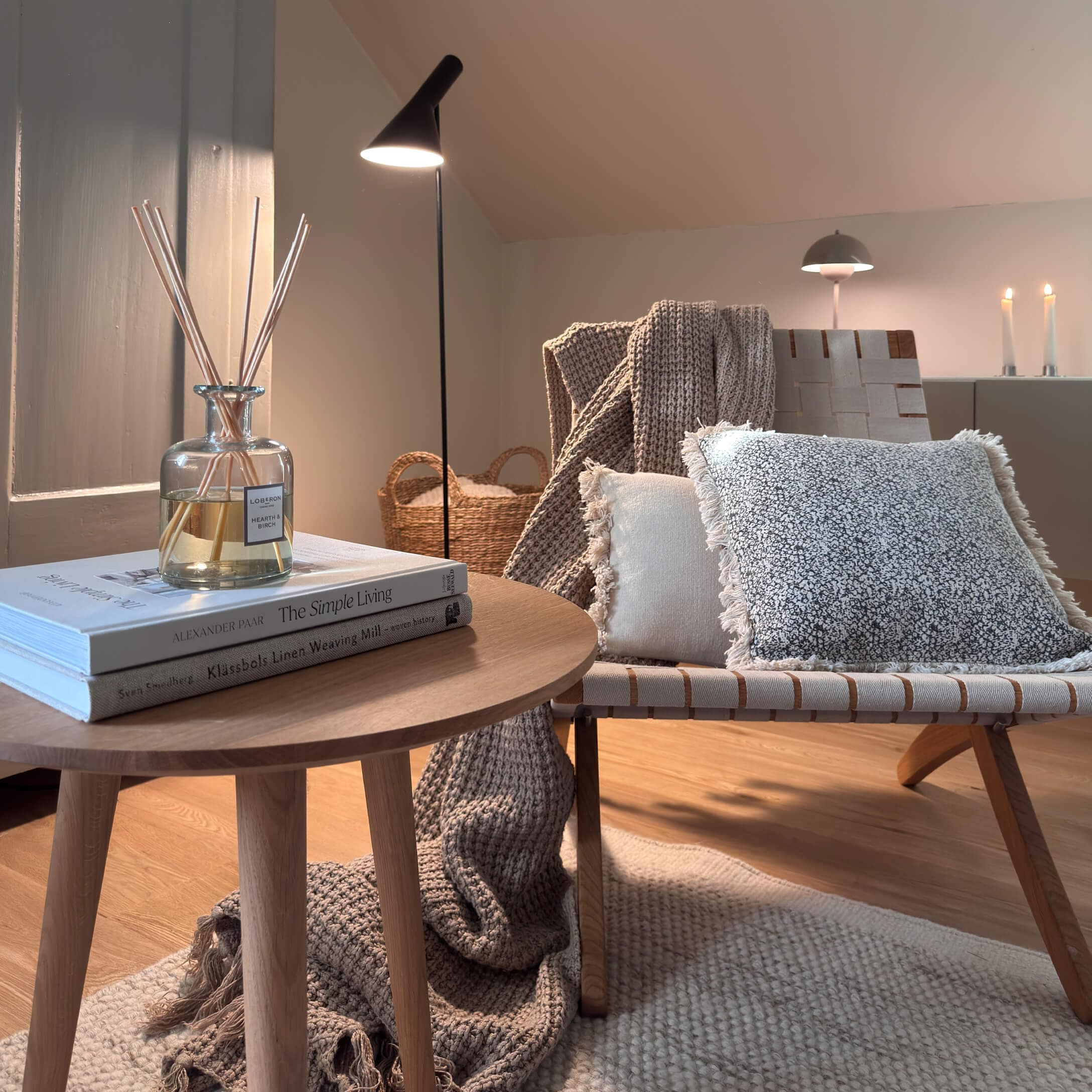 Gemütliche Ecke mit Holztisch, Stehlampe und weichen Kissen in natürlichen Farben für Wohnkomfort.