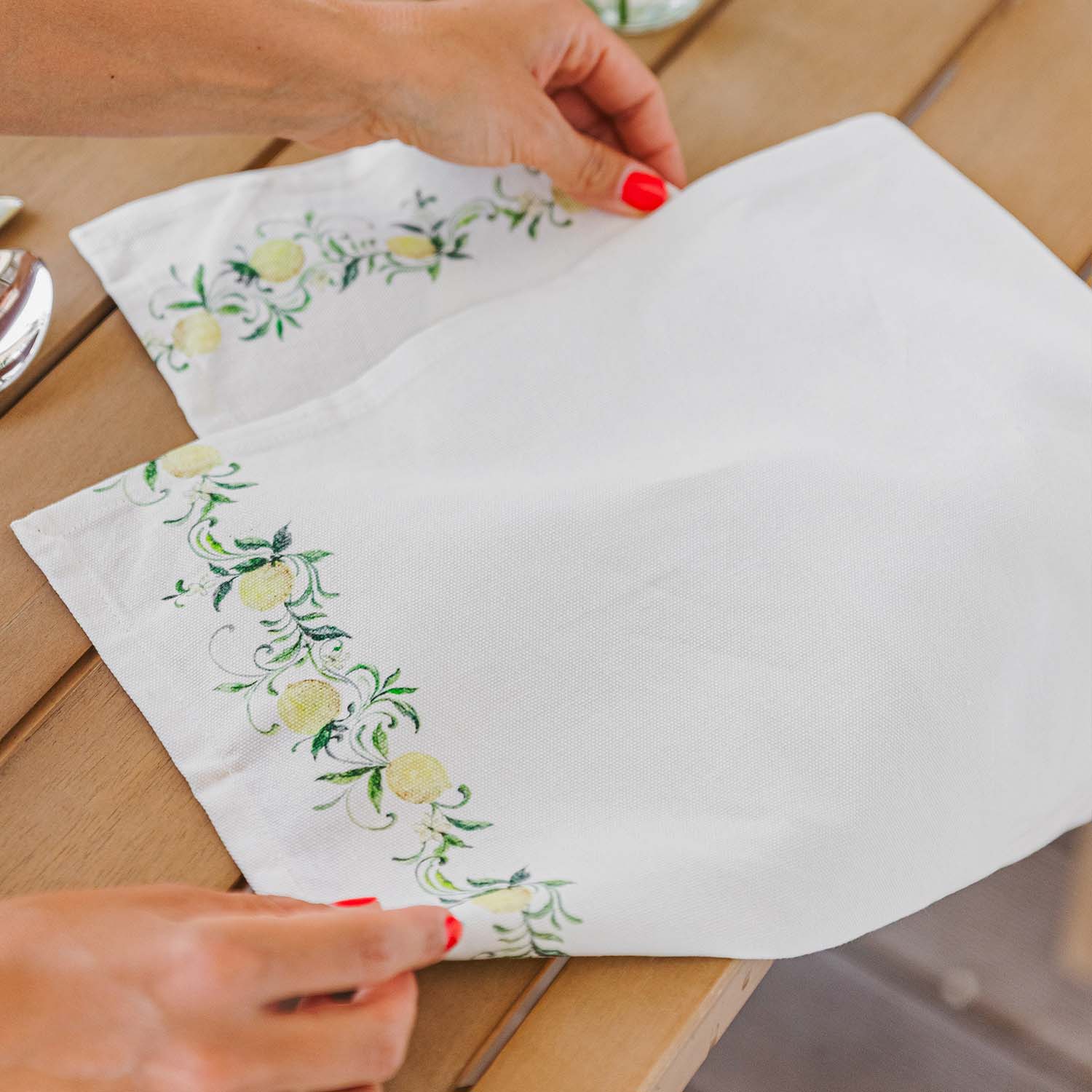 Weisse Leinenserviette mit grün-gelbem Zitronenmuster auf Holztisch, Tischdekoration