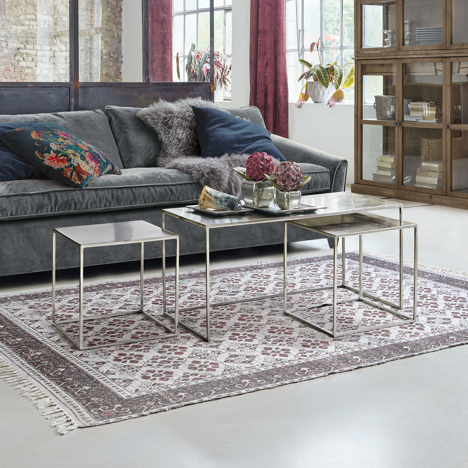 Couchtisch 3er Set Gela Drei Beistelltische mit Glasplatten und Metallrahmen vor grauem Sofa in modernem Wohnzimmer.