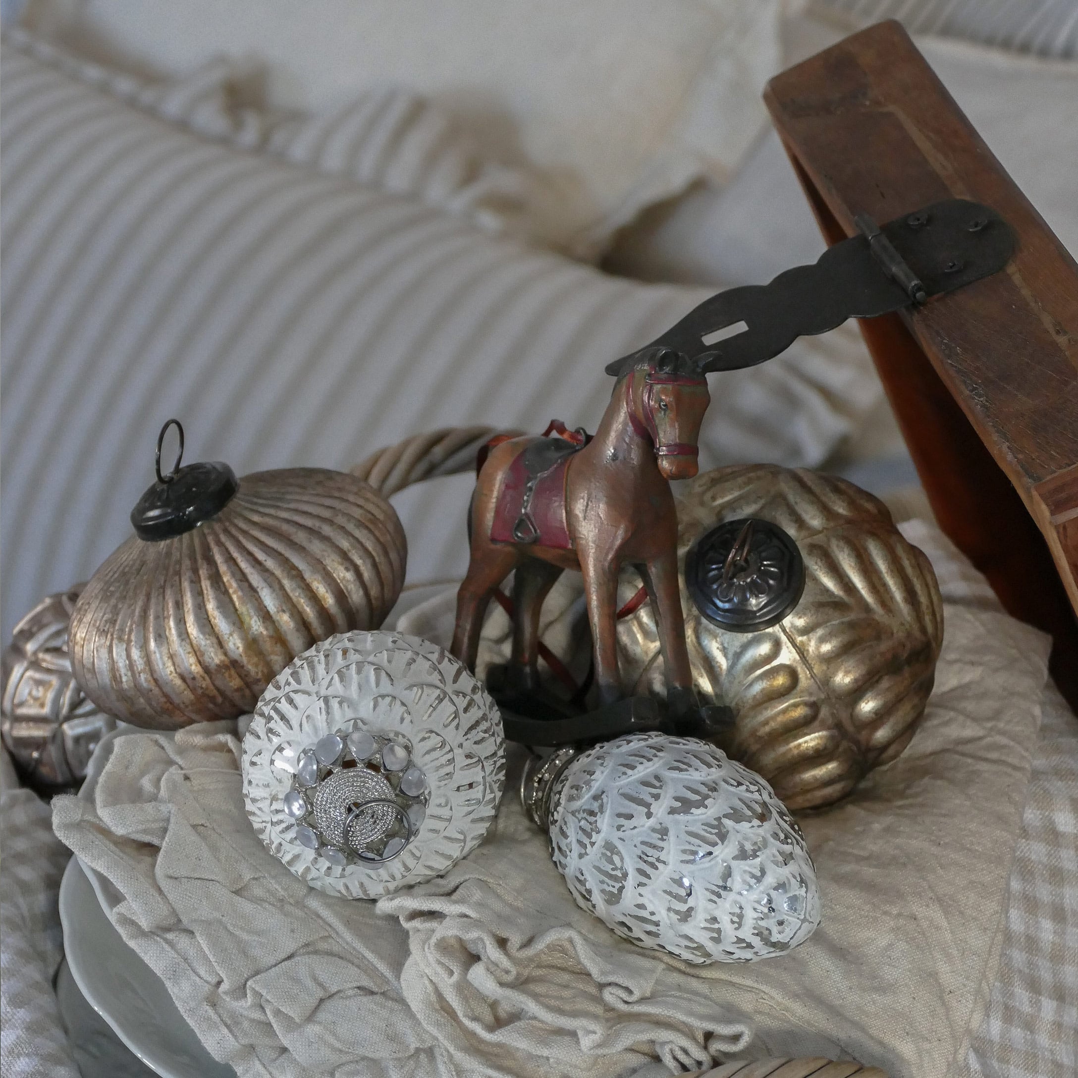 Gold-weisse Weihnachtsdekoration mit Pferdefigur auf beigem Stoff arrangiert