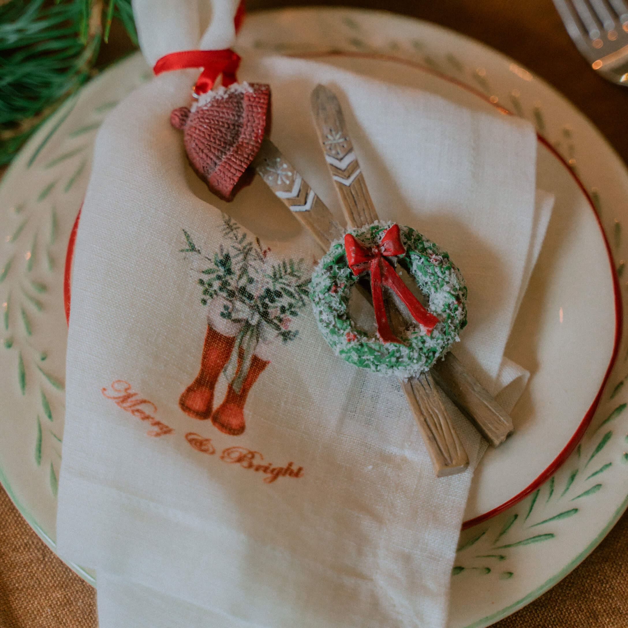 Weihnachtliche Tischdekoration mit weisser Leinenserviette und Holzornamenten mit grünem Kranz