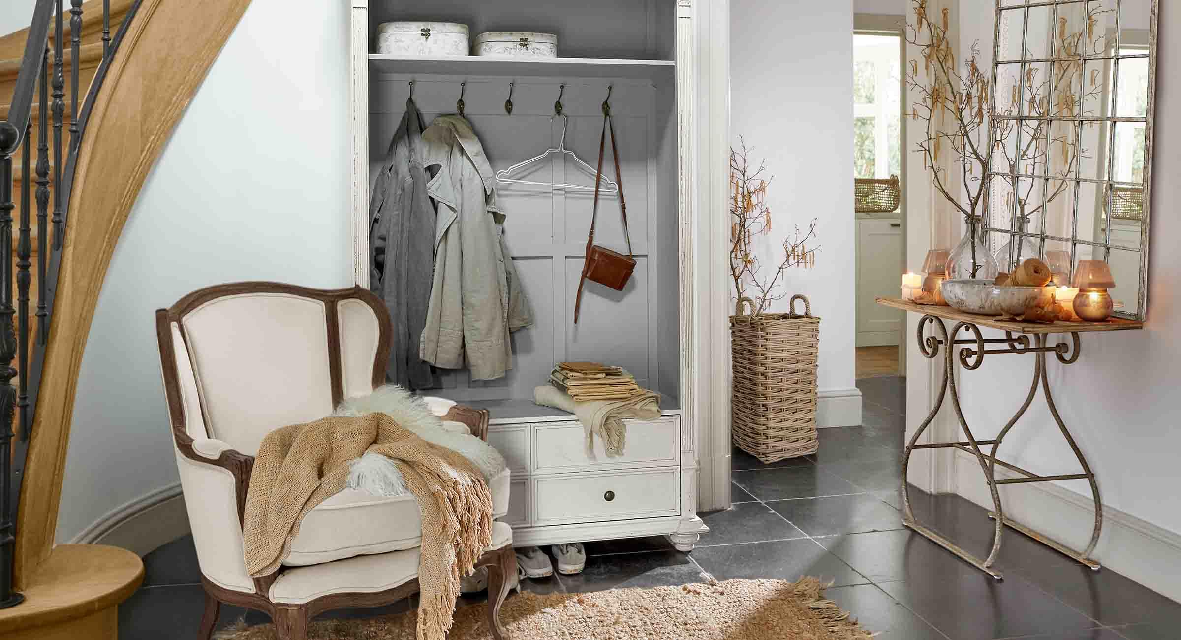 Gemütliche Ecke mit weissem Sessel, Garderobenschrank und Spiegel mit Metallkonsole im Vintage-Stil